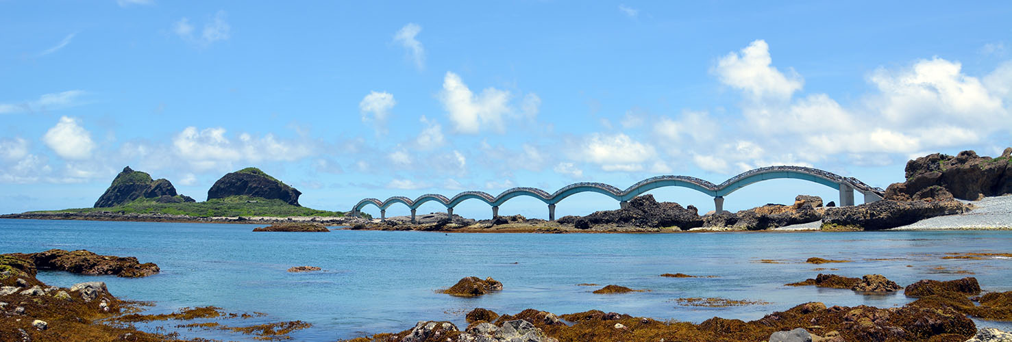 照片中央是一座著名的八拱跨海步道橋，連接著三仙台本島與外島。橋樑呈現波浪型曲線，極具特色，橋身為淡藍色，與天空和大海的色調相呼應，給人協調而又鮮明的視覺效果。