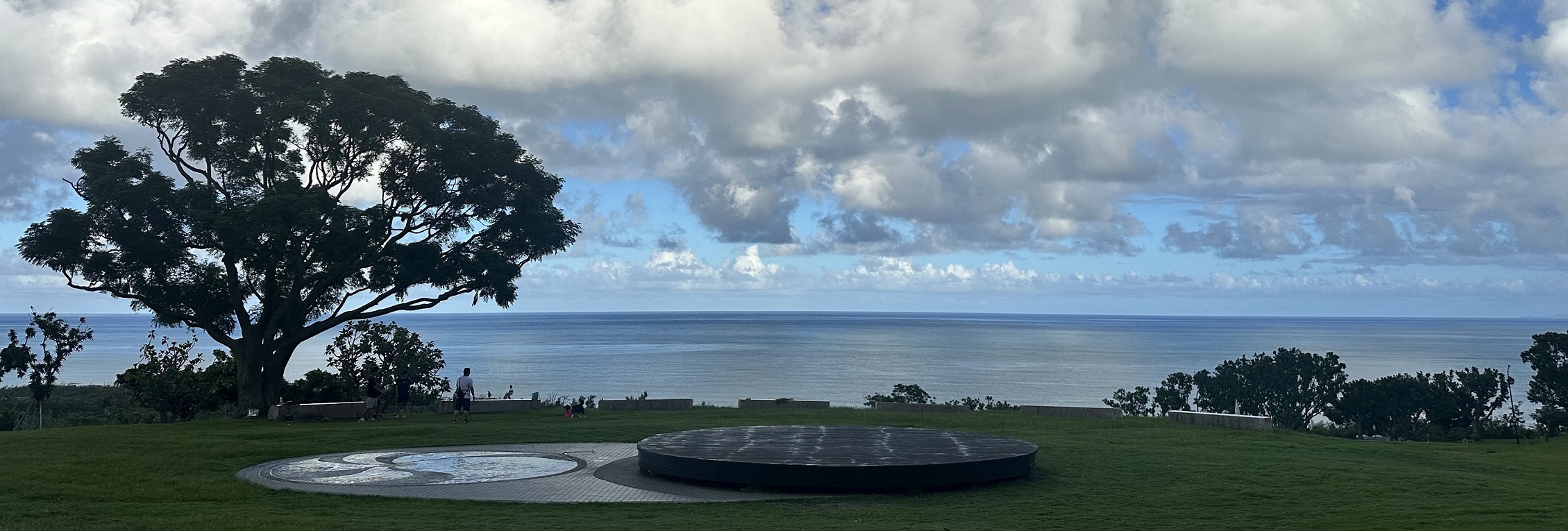 有樹與圓型藝術裝置，可眺望遠方海面